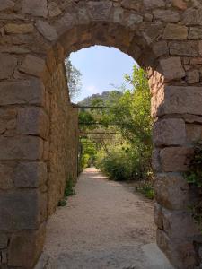 an archway in a stone wall with a dirt road at La Cigale Varoise - Hyères La Plage in Hyères
