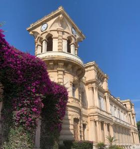 a building with a clock tower with purple flowers at La Cigale Varoise - Hyères La Plage in Hyères