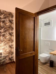 a bathroom with a toilet and a wooden door at Tyche House Castelmola in Castelmola