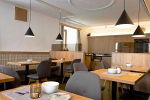 un ristorante con tavoli e sedie in legno e luci di Hotel Garni Löwen a Silz