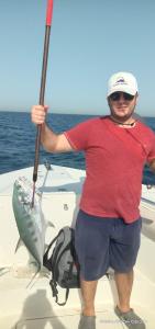 un hombre está sosteniendo un pez en un barco en Dubai fishing trip 5 hours, en Dubái