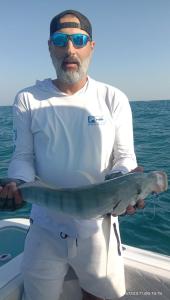 un hombre de pie en un barco sosteniendo un pez en Dubai fishing trip 5 hours en Dubái