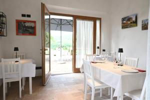 Agriturismo Le Capanne في San Dalmazio: غرفة طعام مع طاولة مع كراسي بيضاء وباب زجاجي
