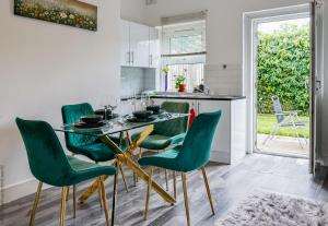 een keuken met een glazen tafel en groene stoelen bij Hampton Court Cottage in Hampton