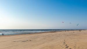 a beach with people flying kites on the sand at Beach Lodge 24 - Noordwijk aan Zee - met eigen tuin in Noordwijk