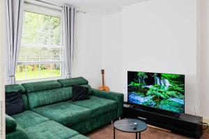 a living room with a green couch and a flat screen tv at Hampton Court Cottage in Hampton