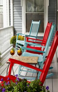 three colorful chairs and a table on a porch at Brewster House Bed & Breakfast in Freeport