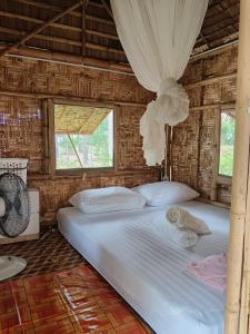 a bedroom with a bed with white sheets and a window at Bamboo homestay at samroiyot in Baanphakrimlay 