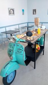 un scooter garé à côté d'une table avec de la nourriture dans l'établissement Villa Mariana Bed and Breakfast, à Saluces