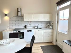 Lónið Apartments في هوفن: مطبخ بدولاب بيضاء وطاولة بيضاء