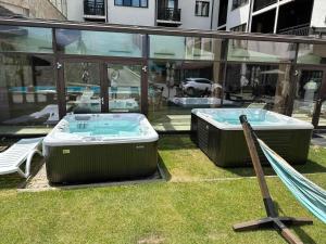 two hot tubs sitting on the grass next to a building at Royal Bansko - Half Board Plus & All Inclusive - Hot Pool & Jacuzzis in Bansko