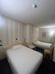 a hotel room with two beds and a chair at Hotel London in Viareggio