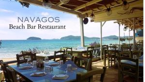 a beach bar restaurant with tables and chairs and the ocean at Villa Nickolas in Paleo Tsifliki