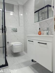 a white bathroom with a toilet and a sink at Atam Suites in Istanbul