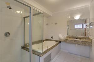 uma casa de banho com uma banheira e um chuveiro em vidro. em Hotel Fredy em Águas de Lindoia