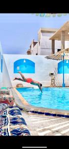 a person diving into a swimming pool at Fnex House in Dahab