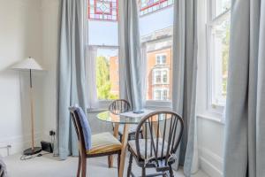 een tafel en 2 stoelen in een kamer met een raam bij Elegant 1BD Victorian Flat Hampstead Heath! in Londen