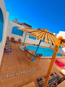 a resort with a pool and an umbrella and chairs at Fnex House in Dahab