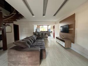 un grand salon avec un canapé et une télévision dans l'établissement Casa encantadora a 100 m da praia de Geribá - WIFI 200MB - TV Smart - 5 Quartos - Garagem - Cozinha equipada - Churrasqueira, à Búzios