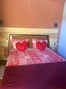 a bed with two red pillows with hearts on it at Pousada Recanto do Tucano in Cavalcante
