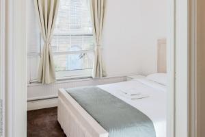 a white bedroom with a bed and a window at Hampton Court Cottage in Hampton