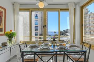 - une salle à manger avec une table, des chaises et de grandes fenêtres dans l'établissement Apartment 13Waves, à Calp