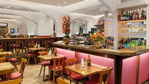 ein Restaurant mit Tischen und Stühlen und eine Bar in der Unterkunft Hotel Deutsche Eiche in München