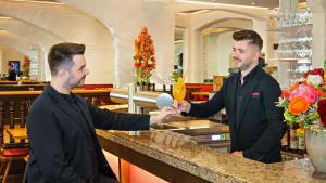 two men shaking hands at a bar in a restaurant at Hotel Deutsche Eiche in Munich