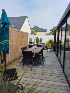 eine Terrasse mit einem Holztisch und Stühlen in der Unterkunft Villa avec piscine intérieure proche des plages du debarquement in Escoville