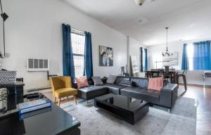 a living room with a black couch and a table at Majestic 3 Bedroom Apartment in NYC! in New York