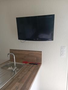 TV a schermo piatto appesa sopra un lavello da cucina di La petite maison dans la prairie a Néant-sur-Yvel Altre 3 foto