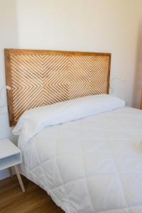 una camera con letto bianco e testiera in legno di Bungalows Mar Menor, paz a orillas del mar a San Javier