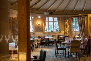 a dining room with tables and chairs and windows at The Devonshire Arms in Baslow