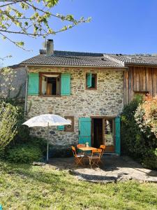 une table, des chaises et un parasol en face d'une maison dans l'établissement Le Domaine d'Arignac, à Arignac