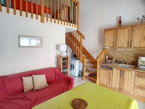 un soggiorno con un divano rosso e una cucina di Pavillon T2 avec grande terrasse a Narbonne-Plage