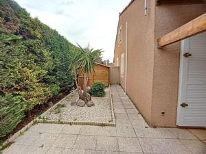 una casa con una palma in un cortile di Pavillon T2 avec grande terrasse a Narbonne-Plage
