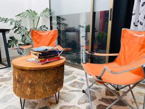 Dos sillas naranjas y una mesa con libros. en Casa compartida ''Central Hostel'' en Medellín