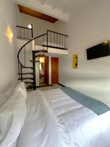 a large white bed with a spiral staircase in a room at Hotel Antiguo Macondo in Villa de Leyva