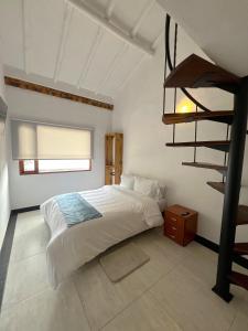 a bedroom with a bed and a spiral staircase at Hotel Antiguo Macondo in Villa de Leyva