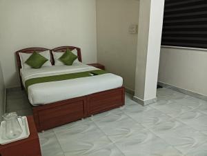 a bedroom with a bed with green pillows on it at Rooms in Chennai