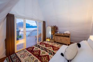 a bedroom with a bed and a window and a desk at The Dewi Kintamani Luxury Glamping and Natural Hotspring in Kintamani