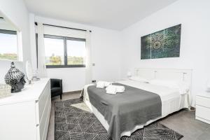 a white bedroom with a bed and two windows at Azahar Sun in Ondara