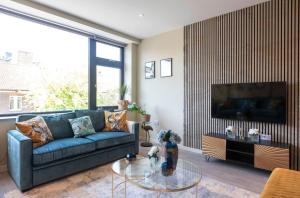 a living room with a blue couch and a tv at Palm Tree House - Birds of Feather in Orpington