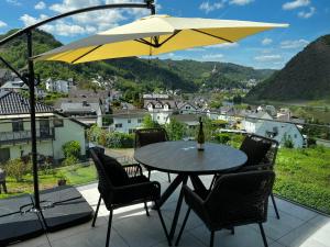 Ferienwohnung Weitblick في كوشيم: طاولة مع كراسي ومظلة صفراء على شرفة