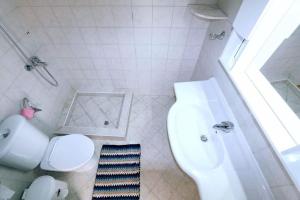 a white bathroom with a toilet and a sink at Apartment in front of the sea in Amoudara Herakliou