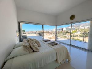 a bedroom with a large bed with large windows at Beautiful modern apartement with Jacuzzi, 1 km from the beach in Torremuelle