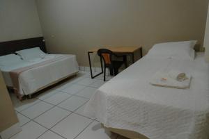 a bedroom with two beds and a table and a chair at Hotel Tropical Garden in Primavera do Leste