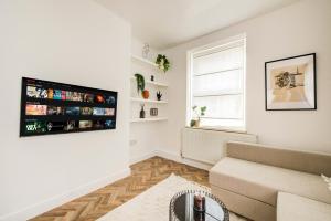 sala de estar con sofá y TV de pantalla plana en BRICK LANE APARTMENT, en Londres