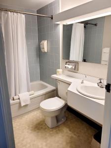 a bathroom with a white toilet and a sink at Claymore Inn and Suites in Antigonish