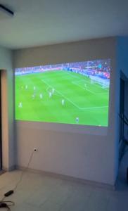 einen großen TV an der Wand mit einem Fußballspiel darauf in der Unterkunft Sunluxvilla ,Heated Pool, IR Sauna in Kaštela